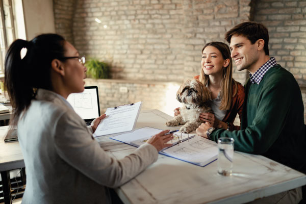 Female mortgage officer at office talking to a couple with a puppy - 5 Mortgage Lending Strategies to Help Your Customers | DG Pinnacle TPO | Miami Wholesale Mortgage Funding Lender