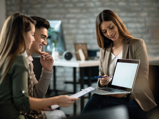 Female mortgage officer at office talking to a couple - 5 Mortgage Lending Strategies to Help Your Customers | DG Pinnacle TPO | Miami Wholesale Mortgage Funding Lender