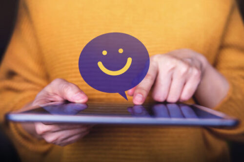 Hands holding a tablet and a smiling face on top | 7 Tips for Managing Client Expectations | DG Pinnacle TPO - Miami Wholesale Mortgage Funding Lender