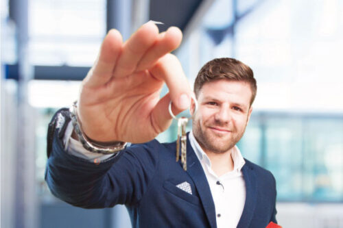 Young mortgage broker holding some keys and a model house - Jumbo Mortgage Loans | DG Pinnacle TPO - Wholesale Division | Miami Mortgage Lender
