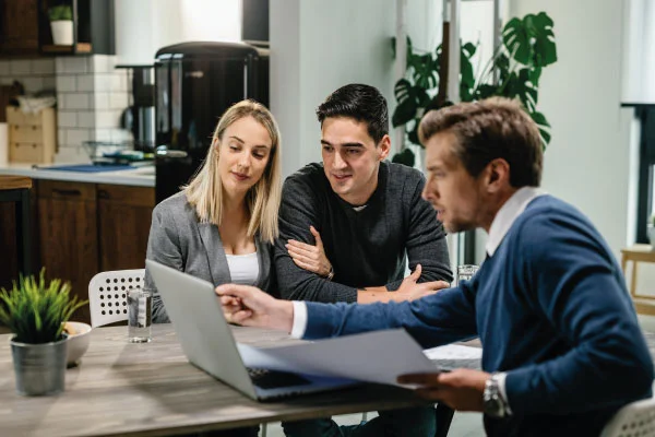 Young couple and mortgage broker using laptop while going through housing plan meeting | The Hidden Benefits to Mortgage Tech | DG Pinnacle TPO - Miami Wholesale Mortgage Funding Lender