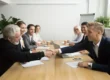 Group of people having a meeting and two of them shaking hands over the desk | MBA urges federal rollback of mortgage rules | DG Pinnacle TPO - Wholesale Division | Miami Mortgage Lender