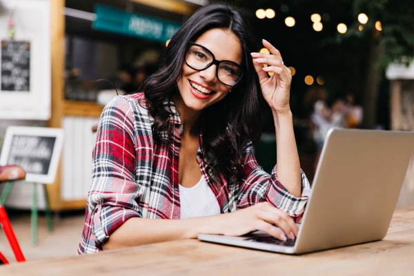 Beautiful freelancer woman smiling next to her laptop | DG Pinnacle TPO - Miami Wholesale Mortgage Funding Lender